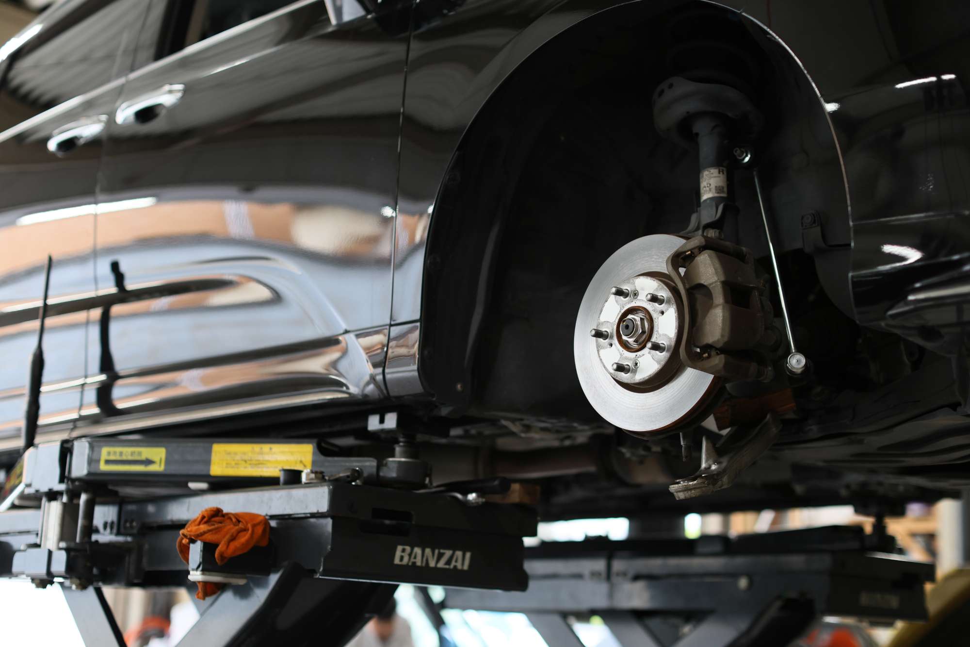 リフトアップされた車のブレーキディスクとホイール整備作業