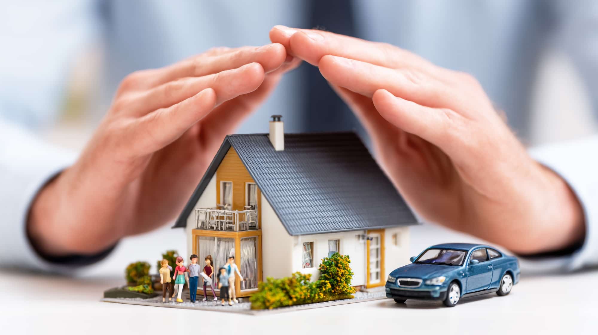 手で家族と家と車を保護している保険のイメージ