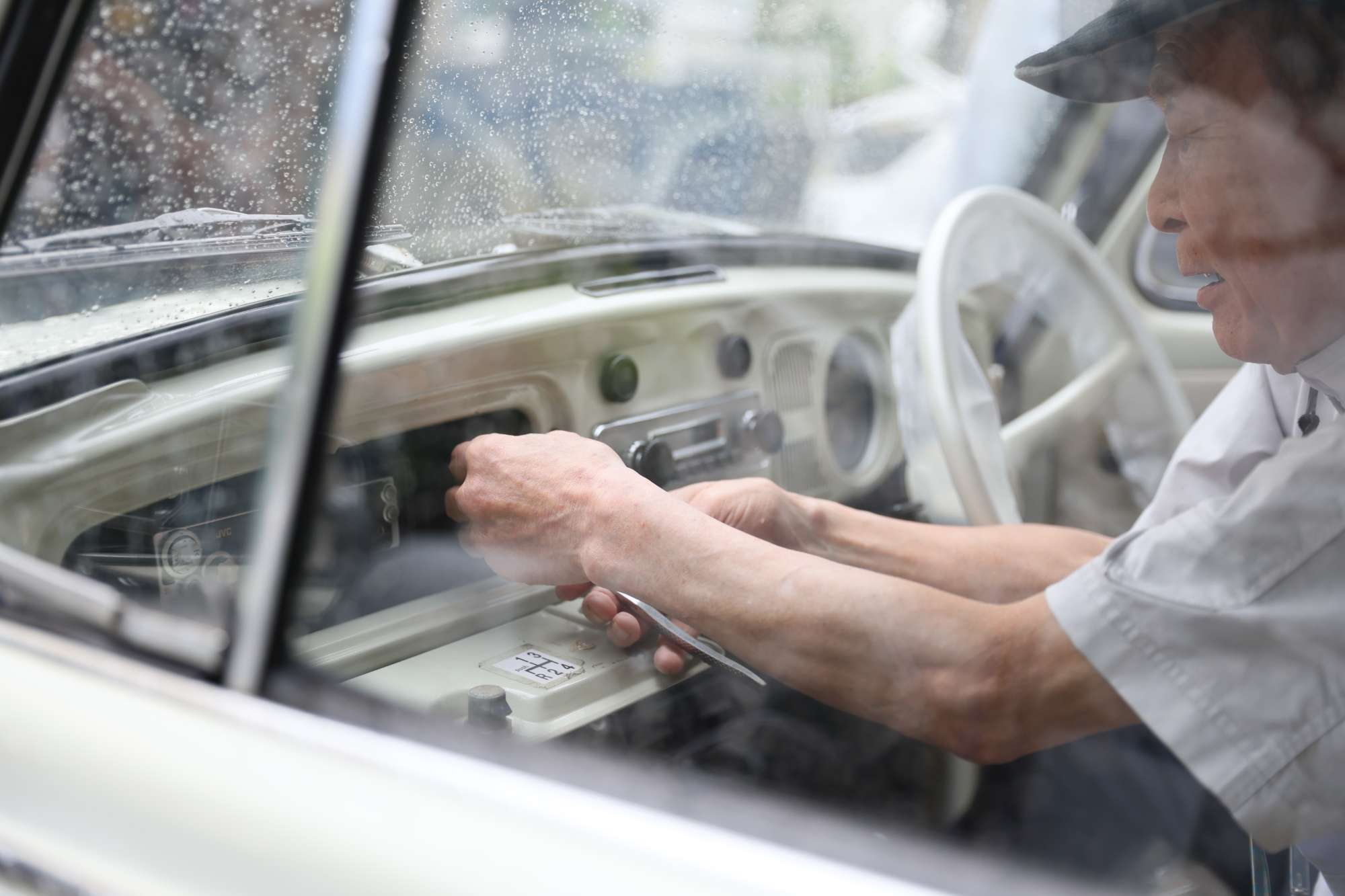 白いクラシックカーの整備作業を行う男性