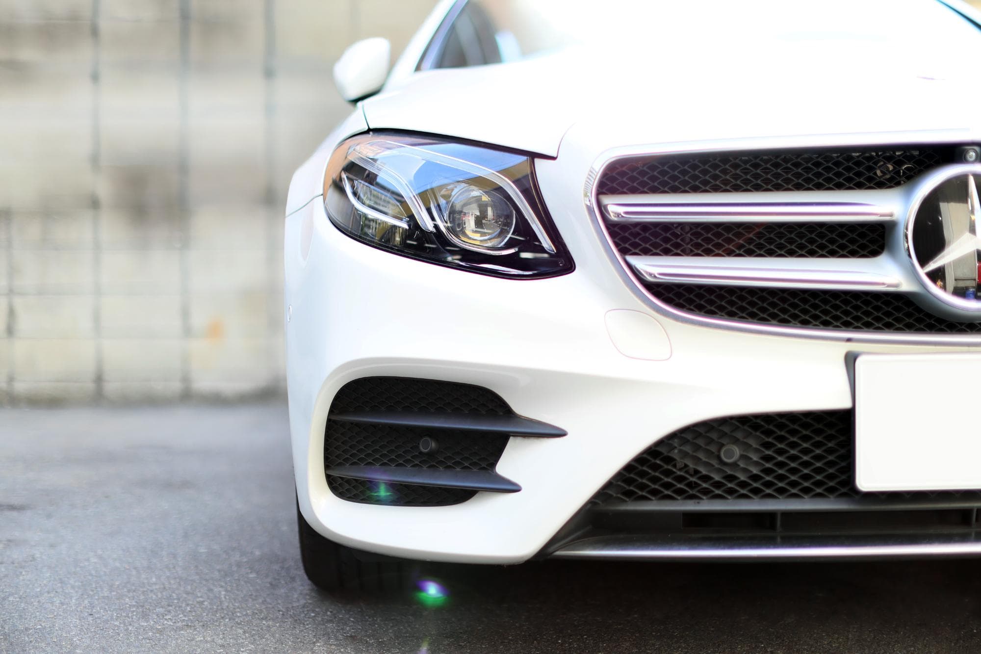 駐車場に停車中の白い高級セダンの正面部分
