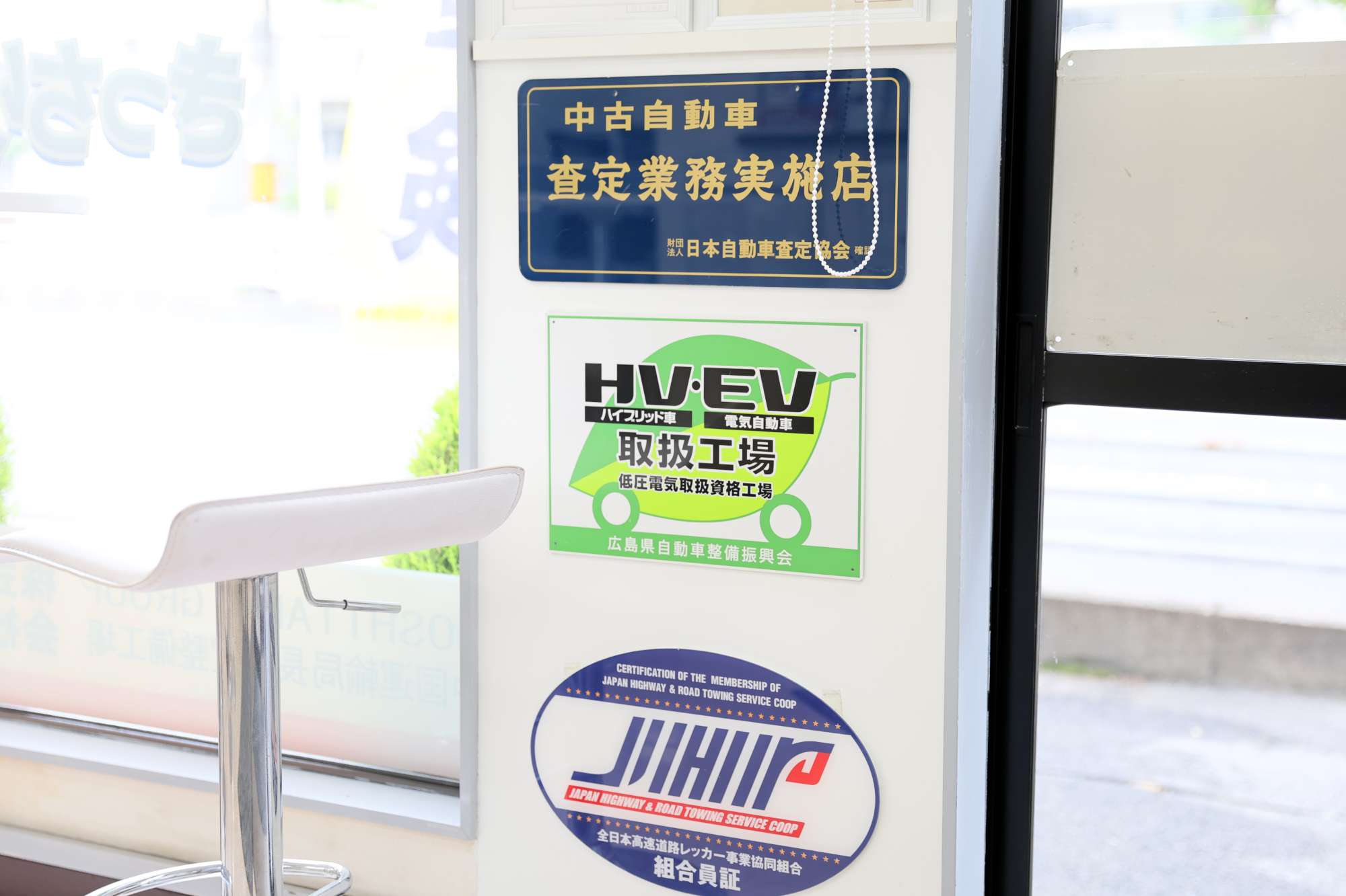 自動車整備工場の認証プレートと証明書が壁に掲示されている様子