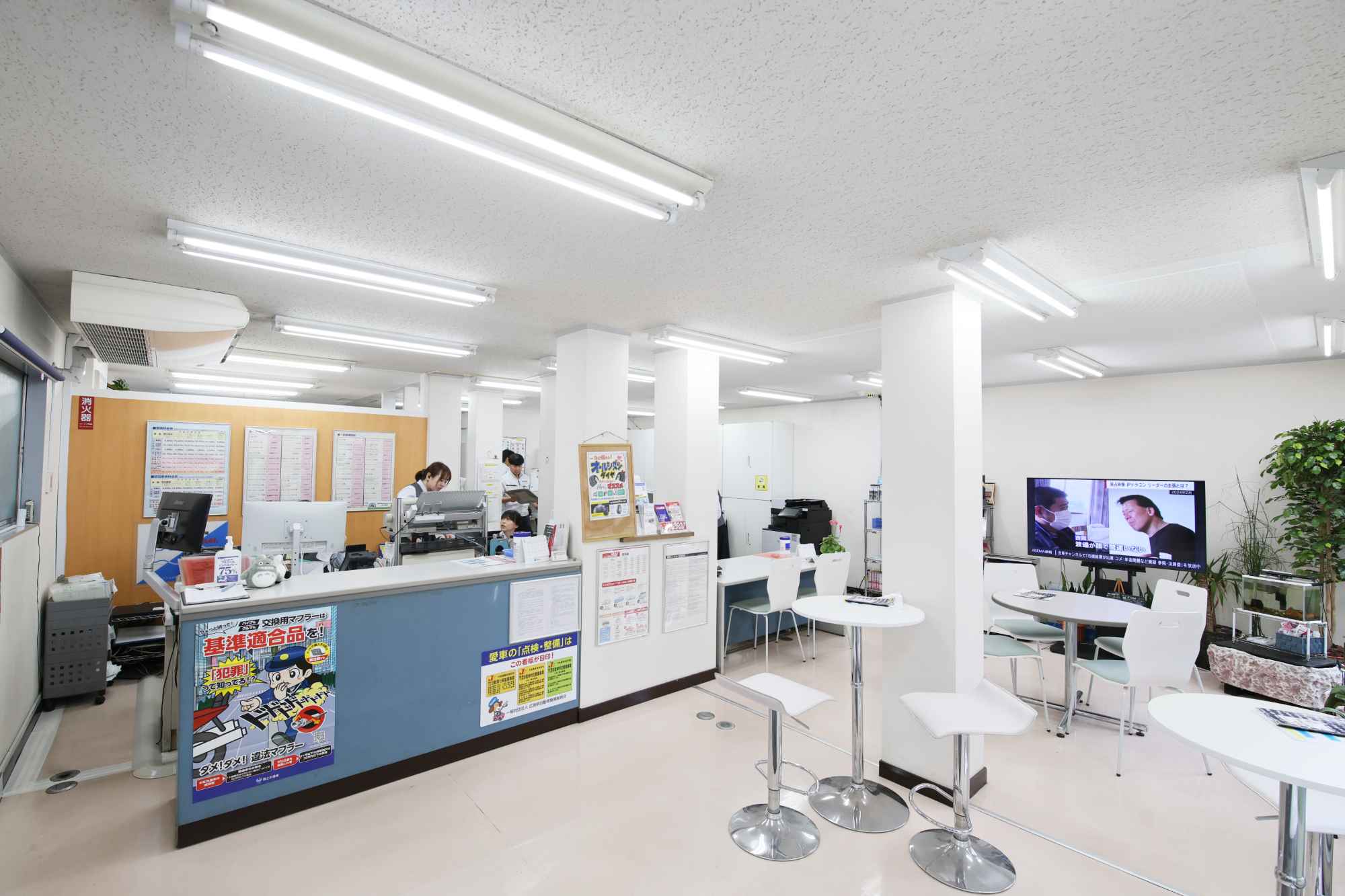 白い受付カウンターで接客する女性スタッフがいる明るいオフィス