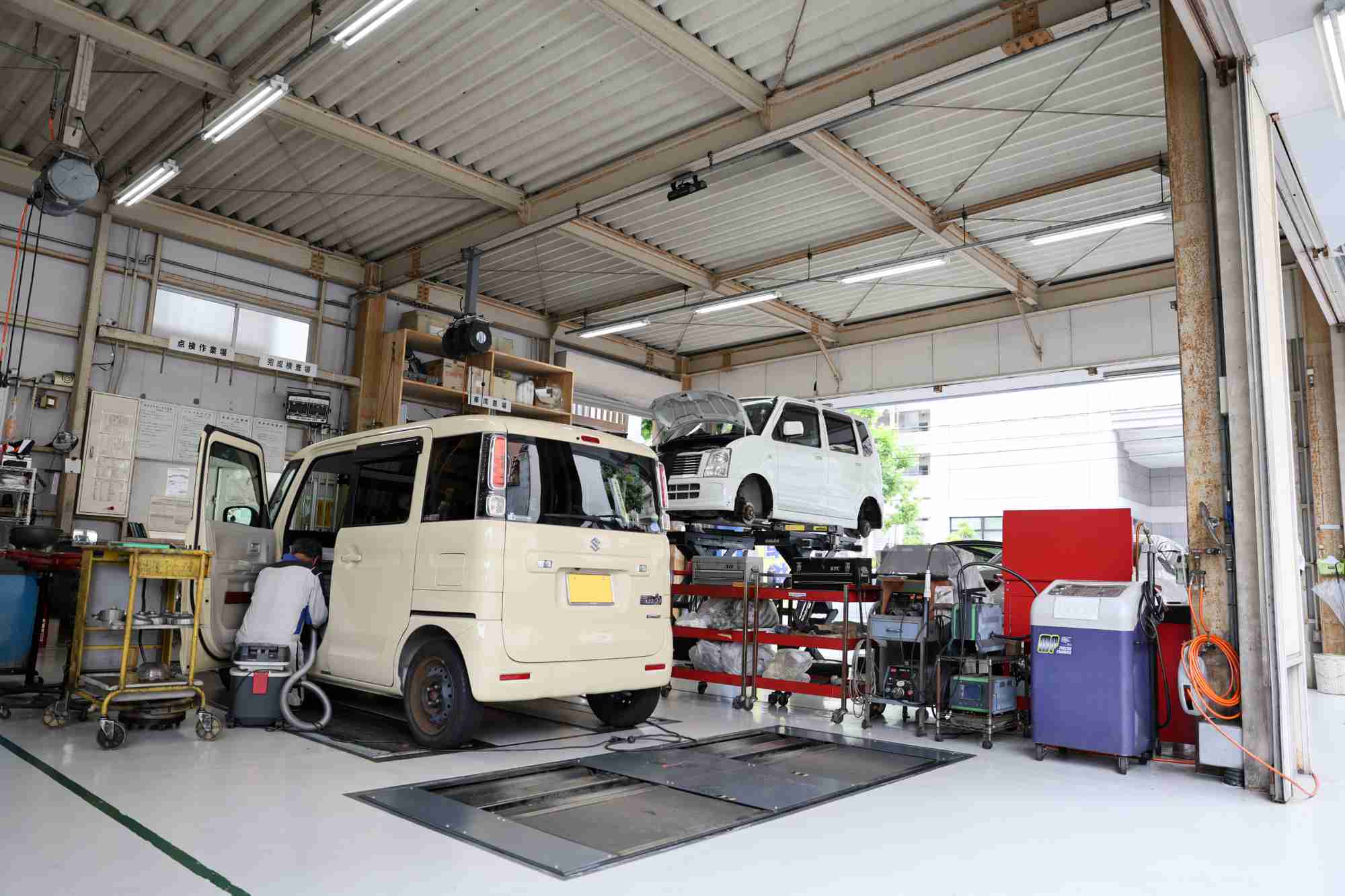 自動車整備工場で白いバンの点検作業をする整備士