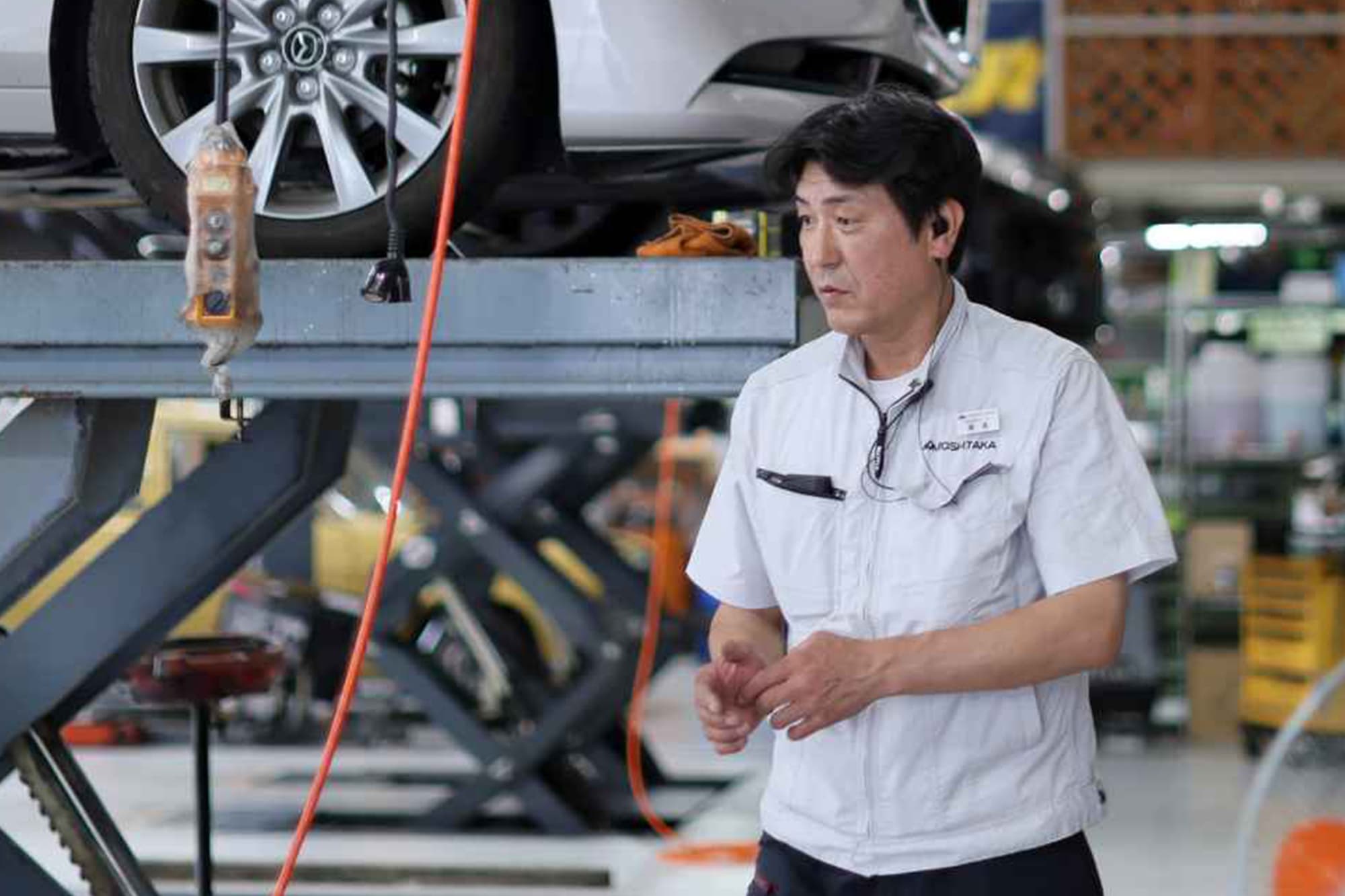 ご提示いただいた単語の訳は、以下のようになります。  日本語訳 「リフトアップされた車の整備作業をする男性整備士