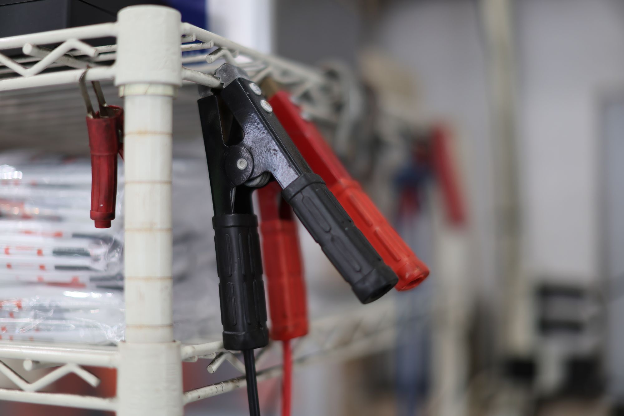 白いラックに掛けられた赤と黒のバッテリークリップ