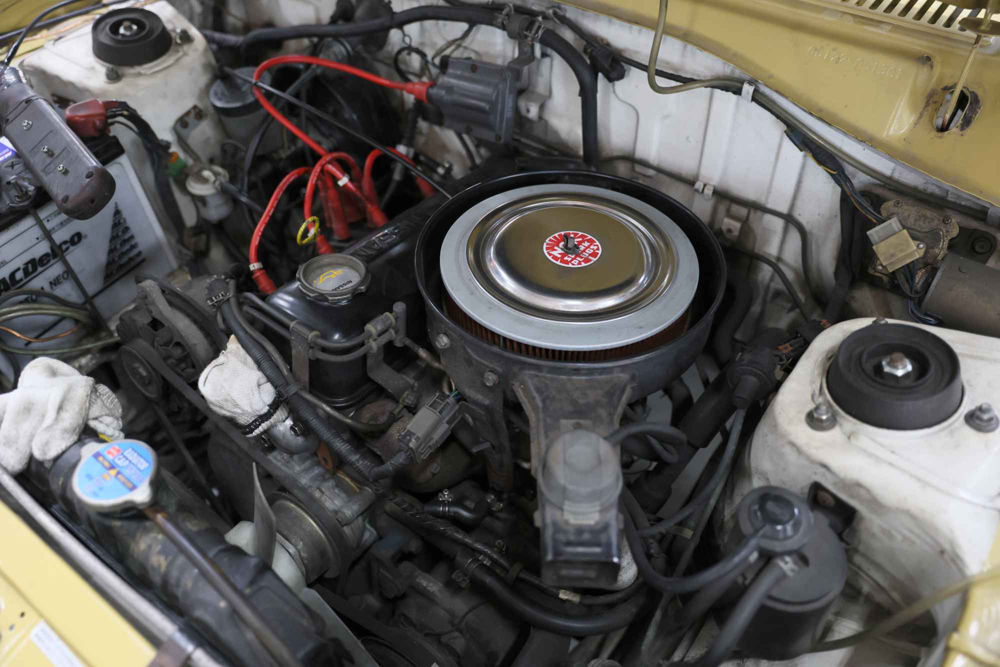 クラシックカーのエンジンルームに配置された円形エアフィルターとエンジン部品