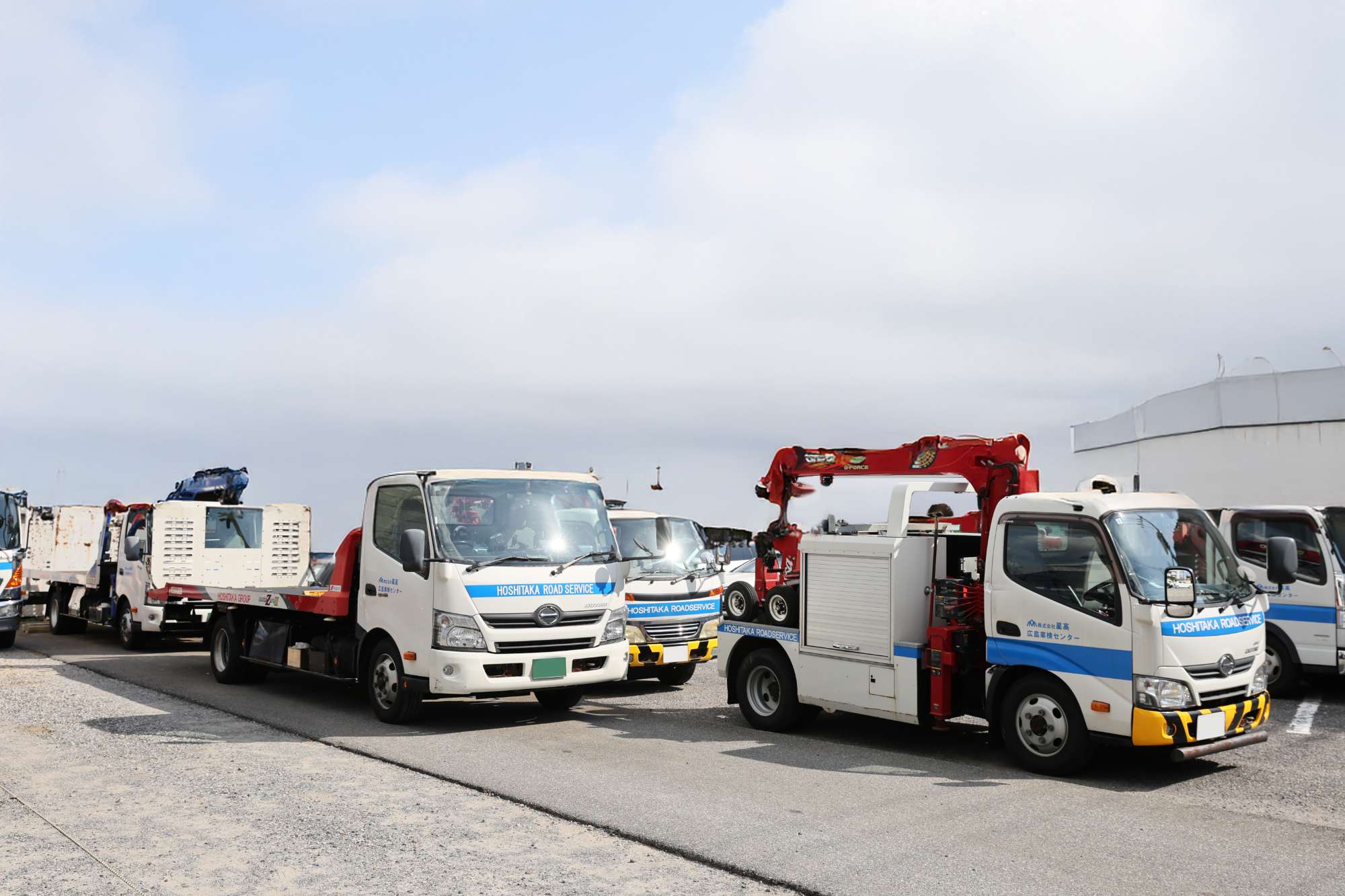 ホシタカ道路サービスの白いレッカー車とトラックが駐車場に並んでいる様子