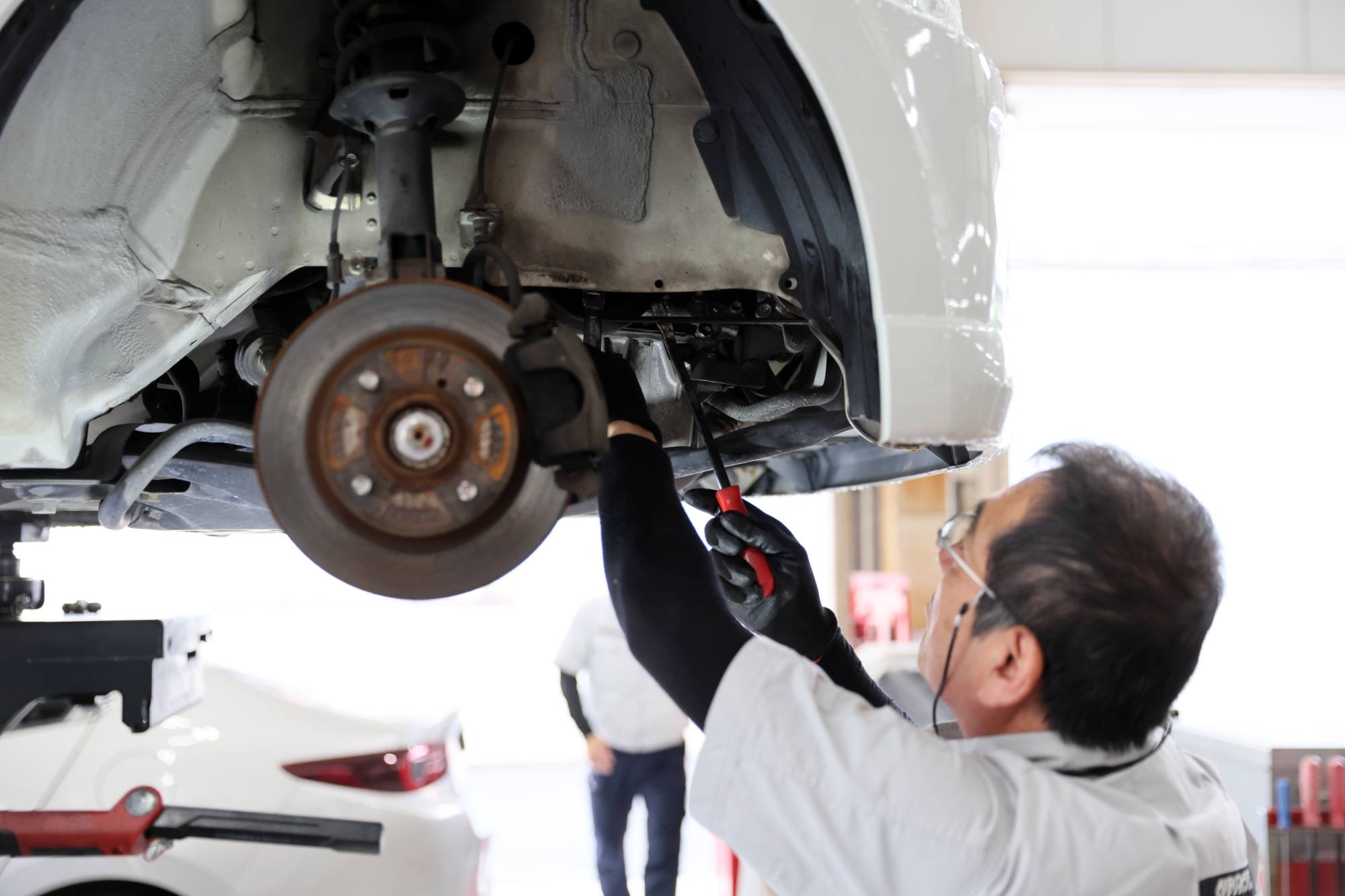 自動車整備工場でブレーキ点検をする整備士