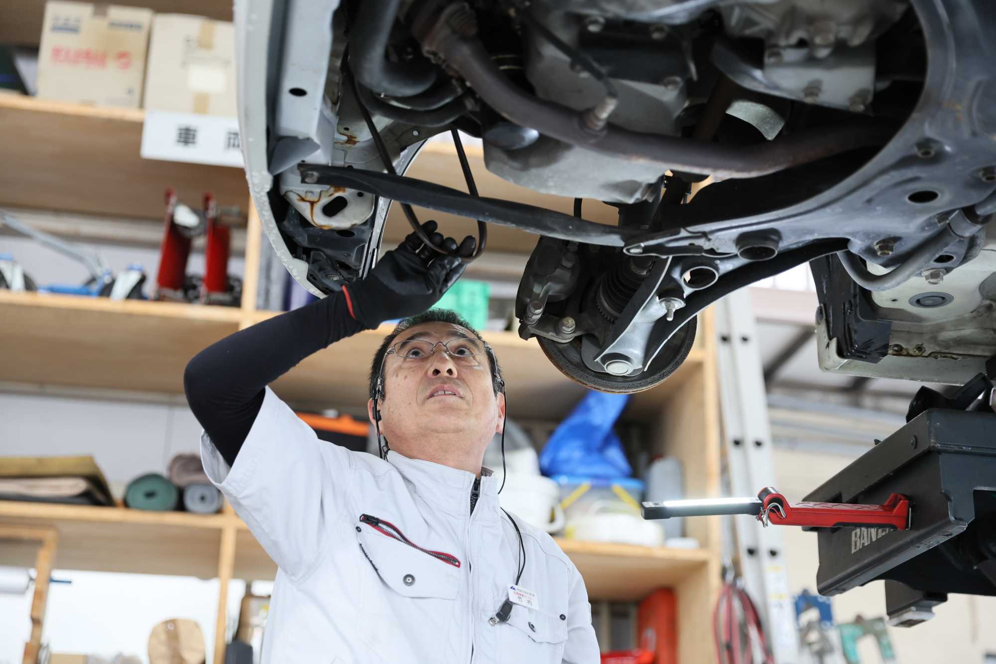 自動車整備工場で車の下回りを点検する作業員