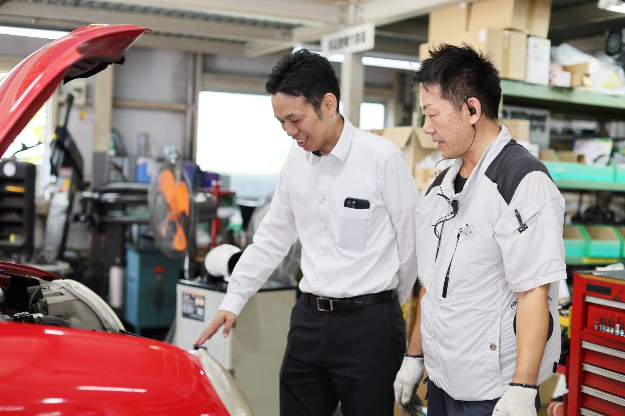 作業員たちが赤い車両のメンテナンス点検を行っているところ