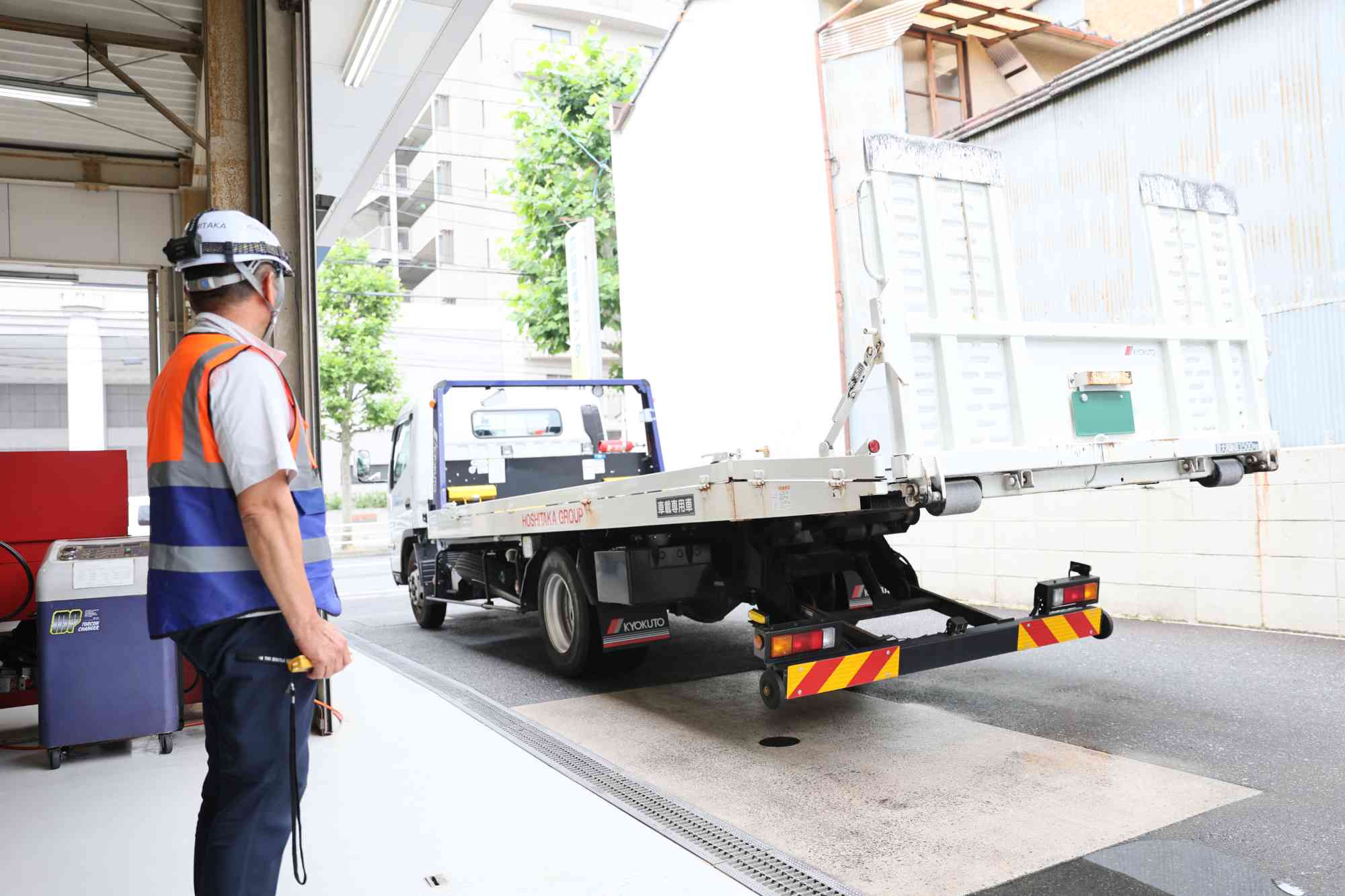 作業場でレッカー車の安全確認をしている自動車救援士の男性