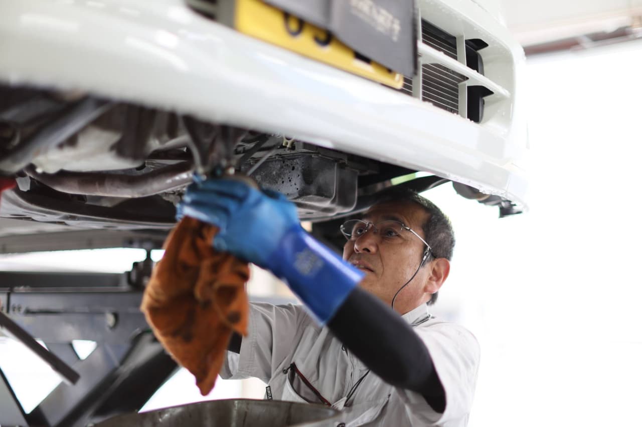 リフトアップされた車両の下で作業する自動車整備士