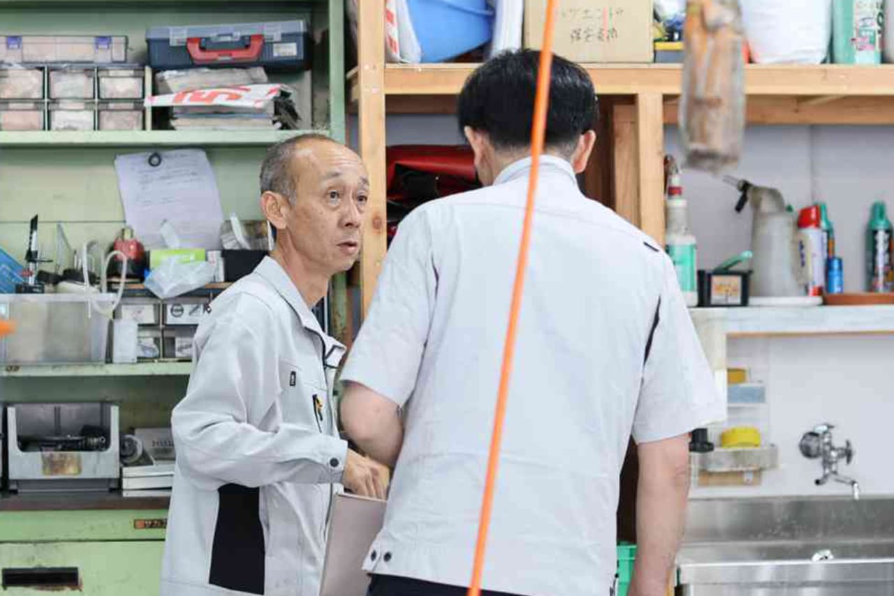 工場で二人の男性が作業について話し合っている様子