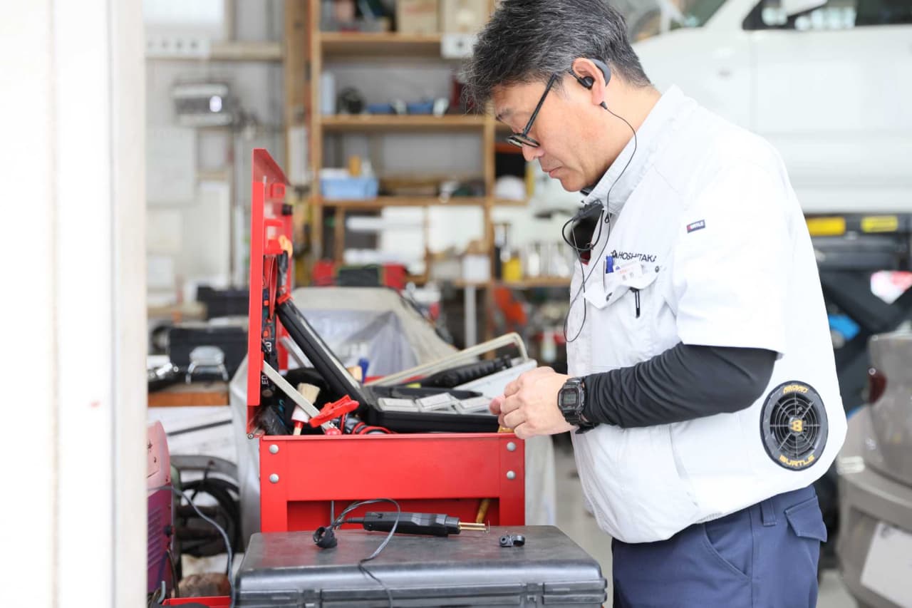 自動車修理工場で赤い検査機器を使用して作業する整備士