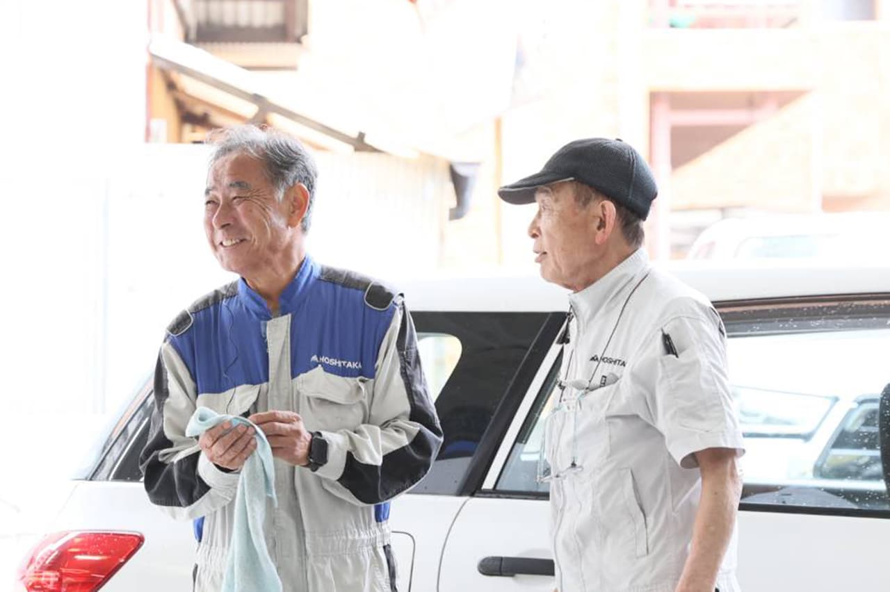 車両メンテナンス現場で作業員同士が相談している風景