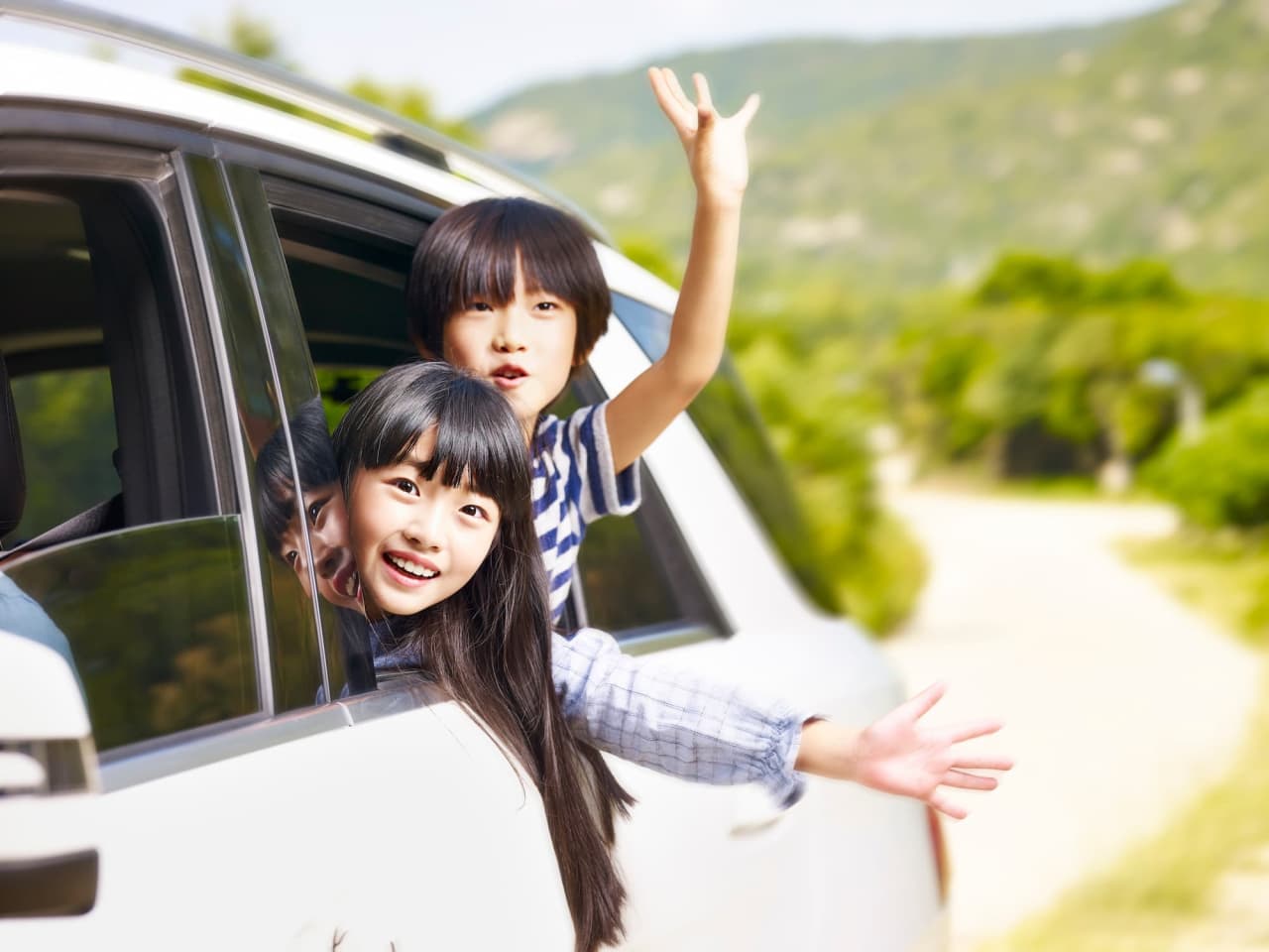 白い車から顔をだしている男の子と女の子